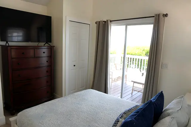 Bedroom at villa 5012 with a chest of drawers, a television and sliding doors to the porch