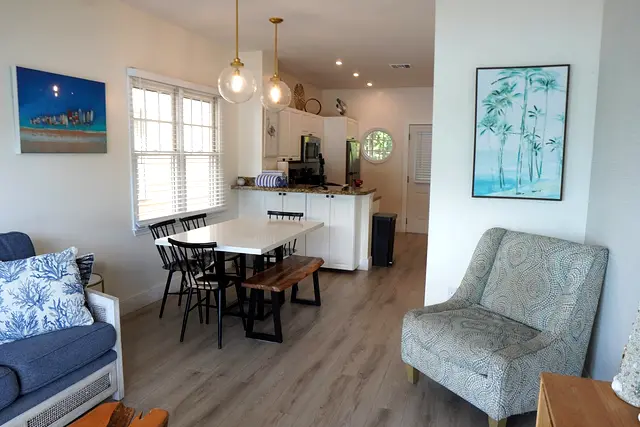 Dining table at villa 5012 under pendant lights, with the kitchen behind and a sofa alongside