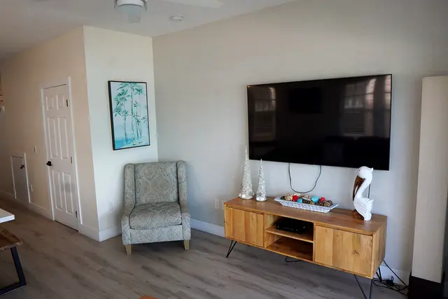 Living room at villa 5012 with a wall-mounted television above a wooden sideboard and an armchair
