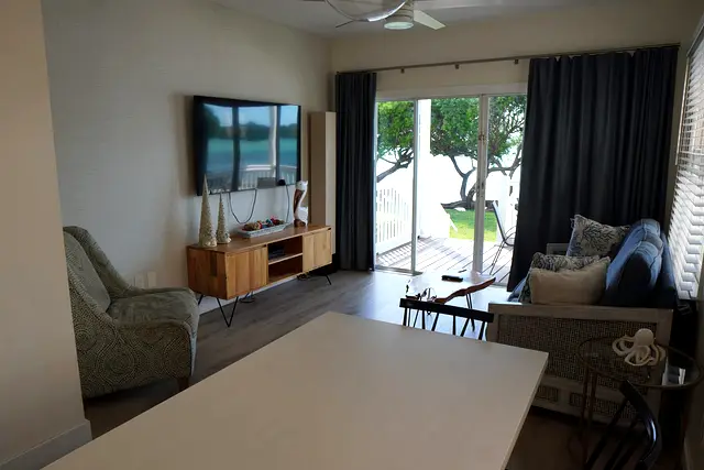 Living room at villa 5012 with a television and sliding doors onto the porch, with the water beyond